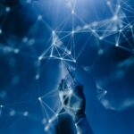 AI in the cloud: A robotic hand touches an abstract blue digital network, representing intelligent automation and optimised data operations.