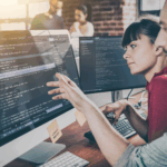 Two software developers collaborating on code in a modern office, illustrating DevOps teamwork and agile development.