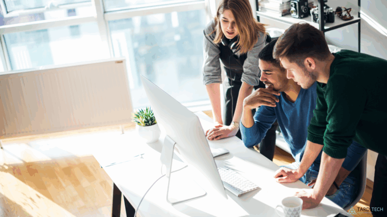 Startup coworkers collaborating at a computer, reviewing cloud infrastructure dashboards to represent Kubernetes adoption for startups.