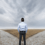A person standing at a crossroads under a cloudy sky, symbolizing strategic choices in cloud and infrastructure management.