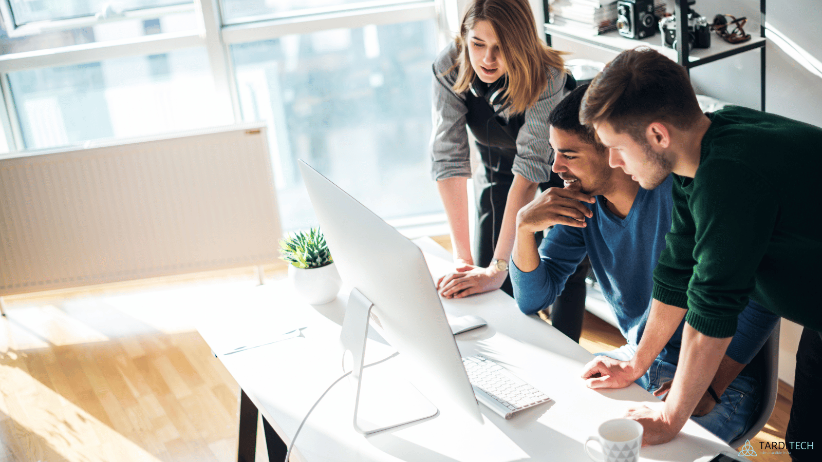 Startup team collaborating at a computer, representing Kubernetes adoption and cloud infrastructure management